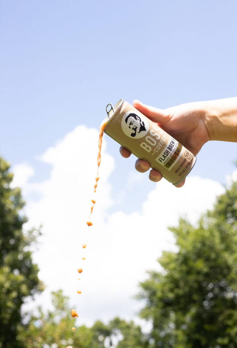 A can of BOSS Coffee being poured, shot looking up at a blue sky