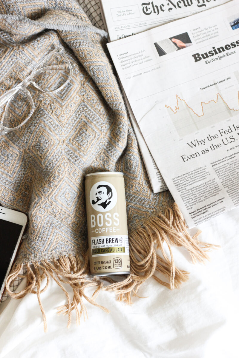 Laying in bed reading the newspaper with a BOSS Coffee