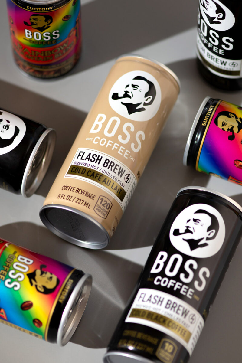 A collection of BOSS Coffee cans laid out next to one another with a play on shadows.