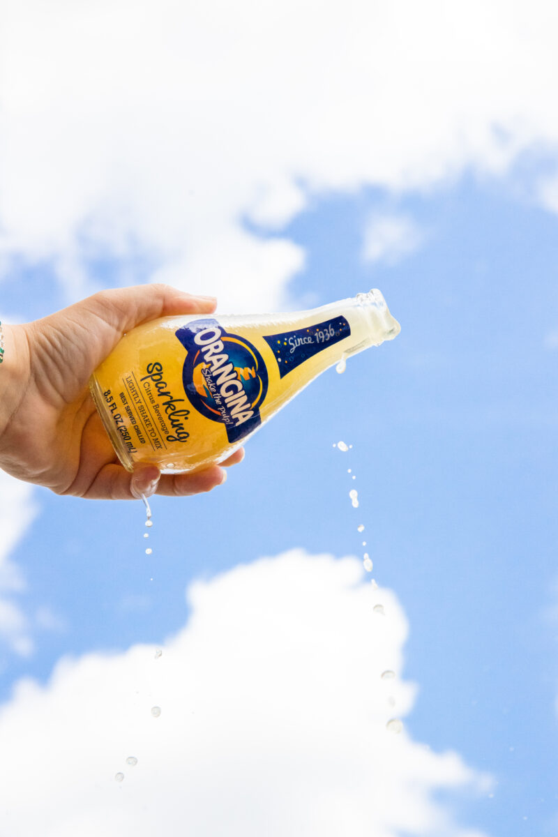 Orangina - Pouring Glass Bottle with the Blue Sky in Background