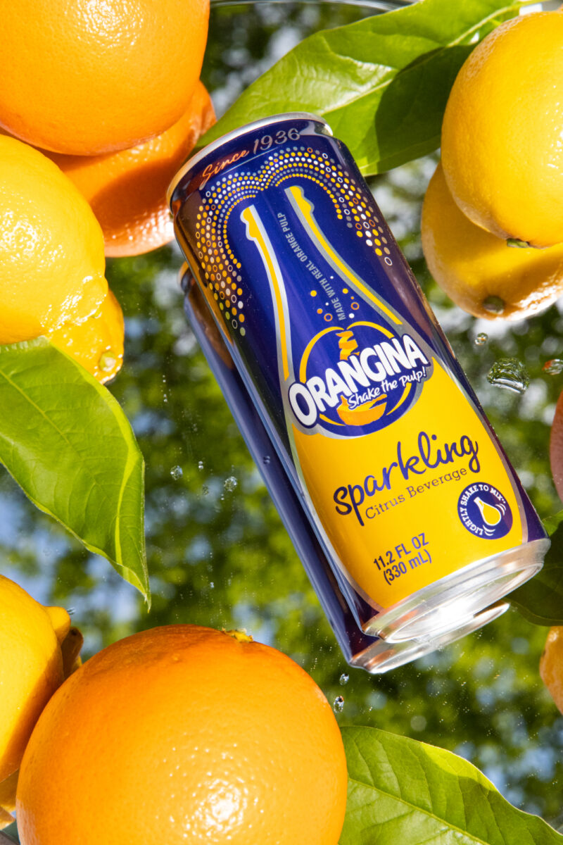 Orangina - Sparkling Can on Mirror with Oranges