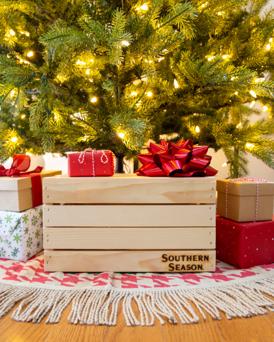 A Southern Season wooden crate, amongst other wrapped gifts under a lit christmas tree