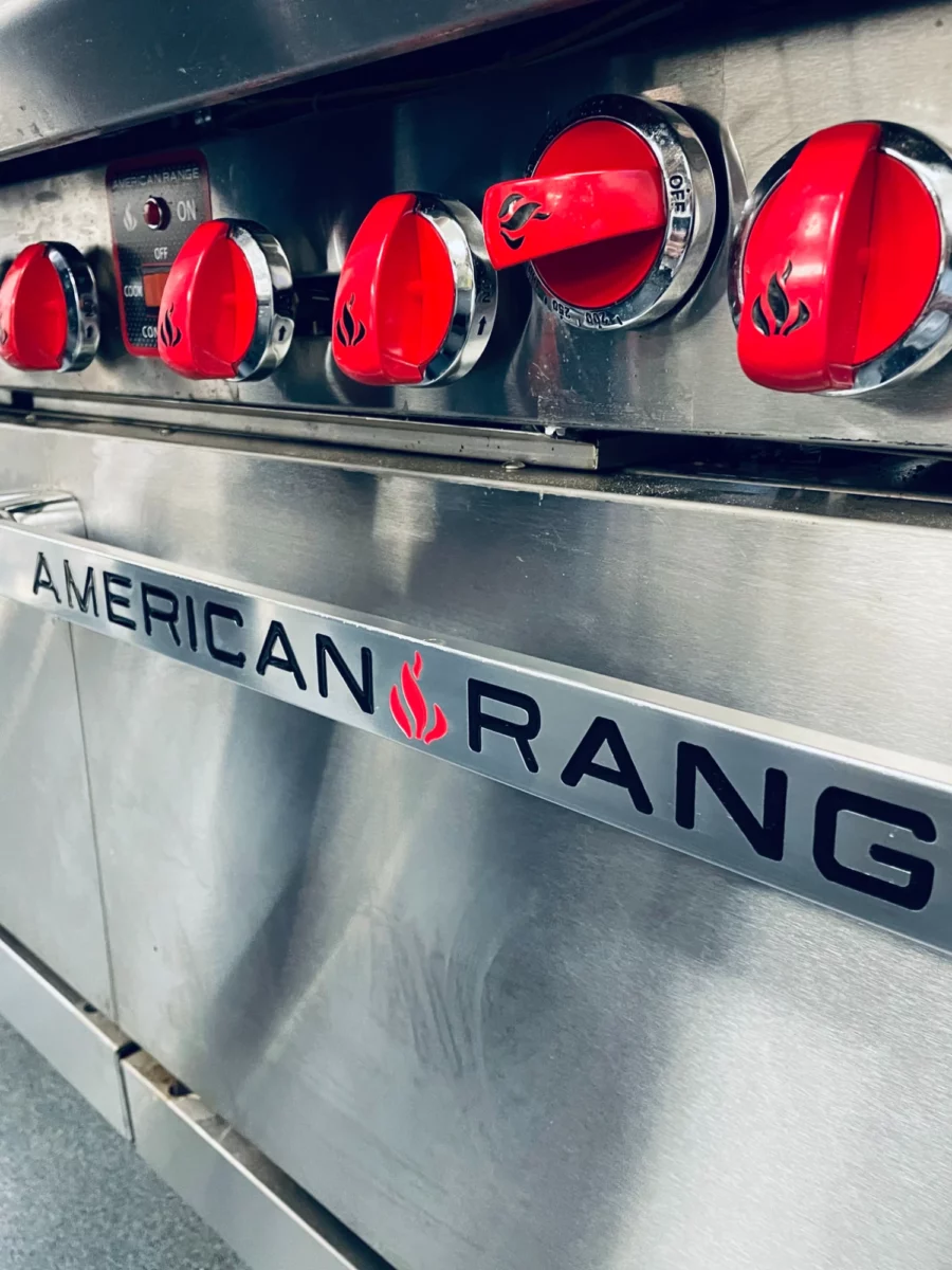 American Range closeup of the oven door handle and red stovetop knobs