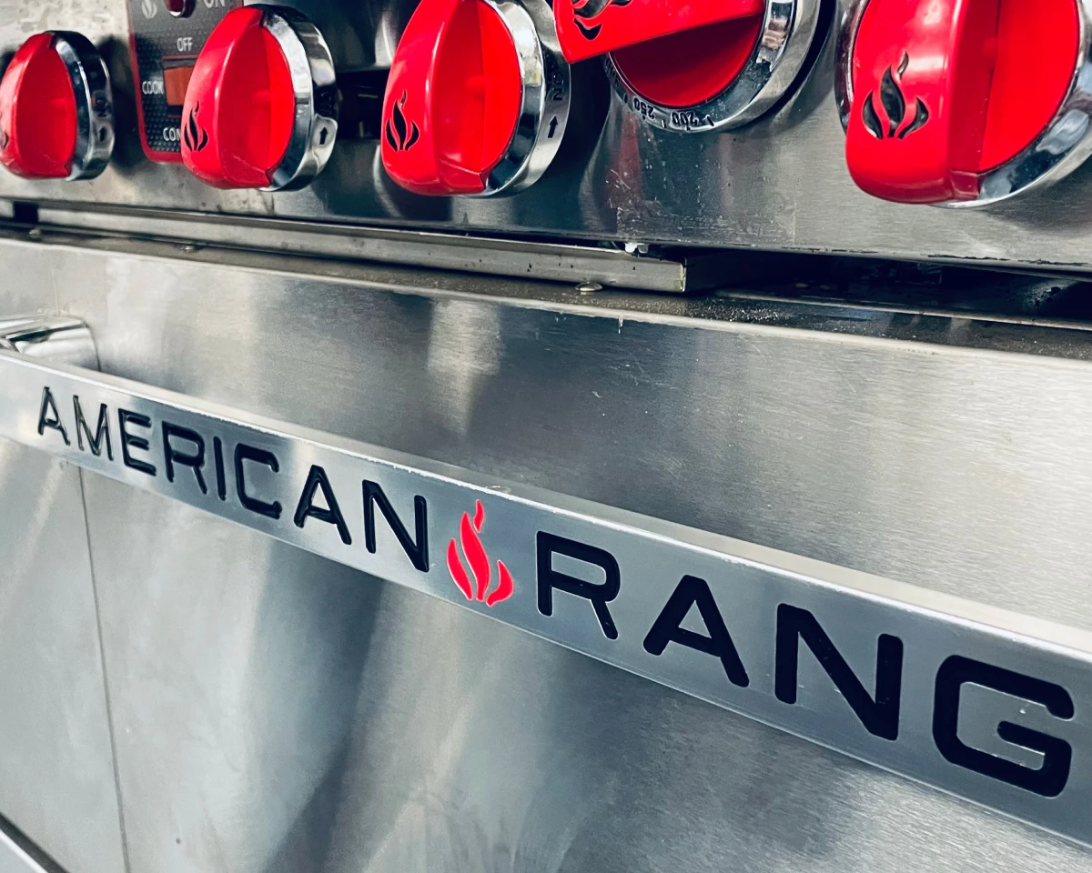 American Range closeup of the oven door handle and red stovetop knobs