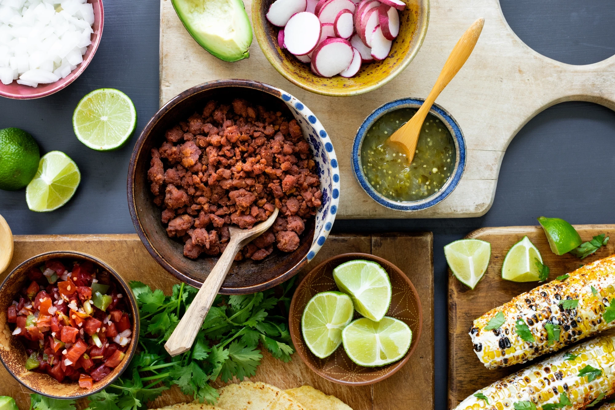 Mr Burgy and Co plant-based taco station with bowls of radishes, onion, salsa, pico de gallo, limes and Mr Burgy plant-based ground beef