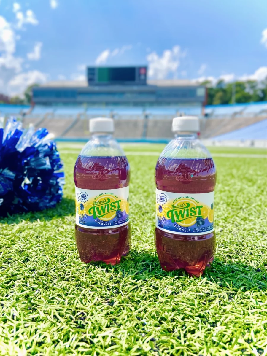 Two bottles of Nature's Twist Blueberry Lemonade sitting on the turf of a football field